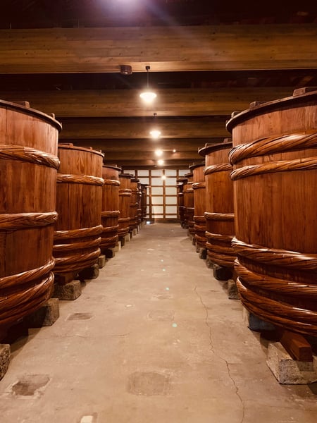 A cellar with large wooden barrels used for shochu maturation.